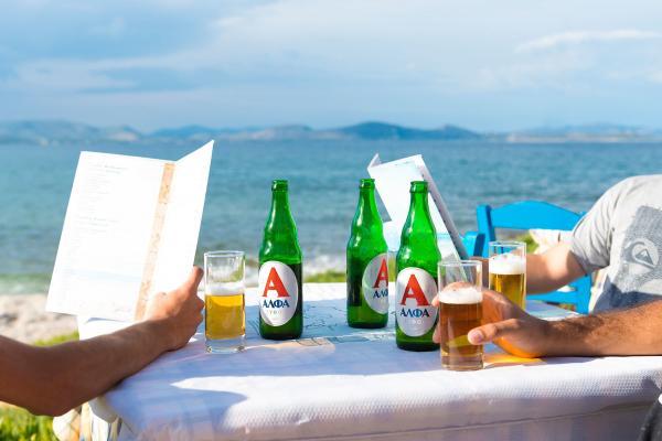 Three guys sitting near the sea drinking a beer